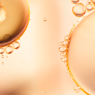 Close-up of oil bubbles on a peach-colored background